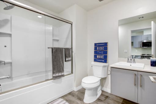 Bathroom of a studio apartment with hot tub and shower combo, single vanity, wood style flooring