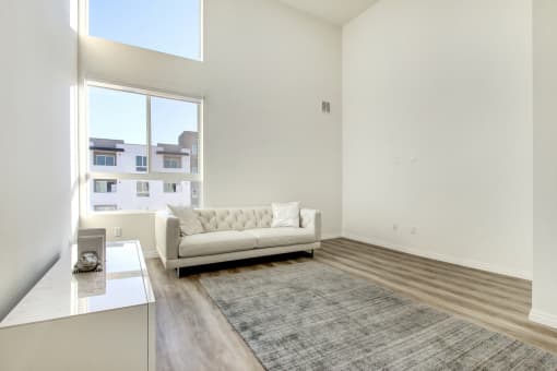 Living and sleeping area of a studio penthouse, large windows, high ceilings, Laminate flooring