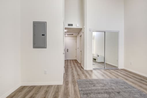 Living and sleeping area with mirrored closet doors, laminate flooring