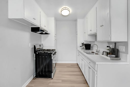 a kitchen with white cabinets and a black stove and a sink