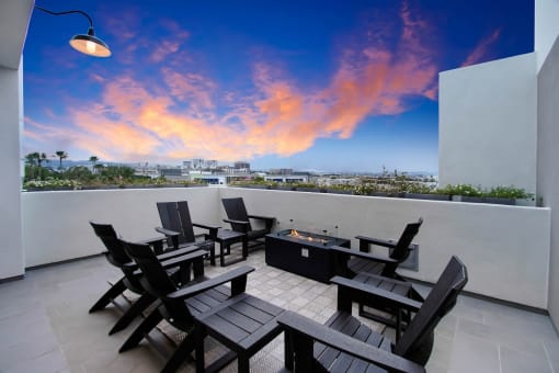 a terrace with a table and chairs and a sunset in the sky