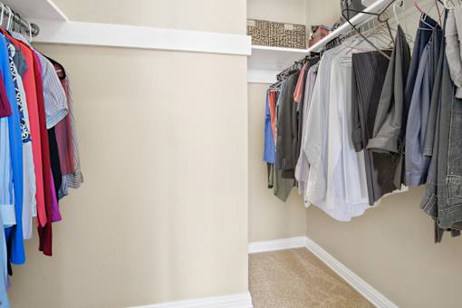 a closet with a rack of clothes and a door to a closet