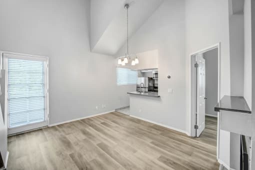 the living room and kitchen of an empty home with white walls and wood flooring