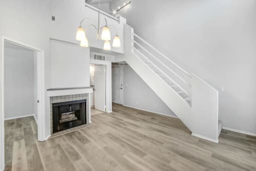 an empty living room with a fireplace and stairs