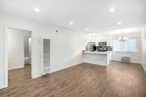 the living room and kitchen of a new home with white walls and wood flooring