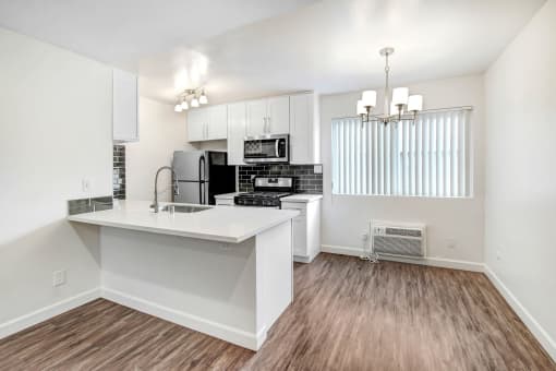 an open kitchen and living room with a white counter top and a refrigerator