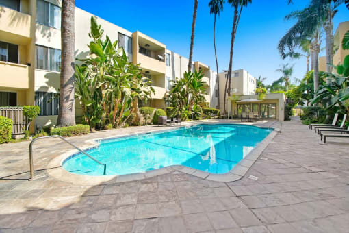 a large swimming pool in front of a hotel with palm trees