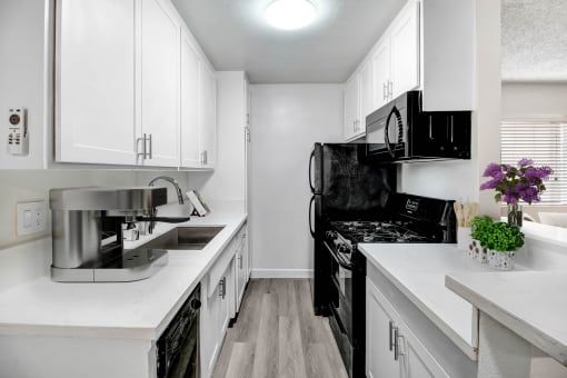 a renovated kitchen with white cabinets and black appliances