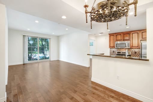an empty living room with a kitchen and a chandelier