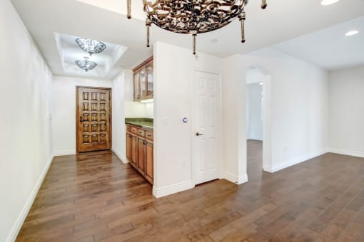 a dining room and kitchen with white walls and a large chandelier