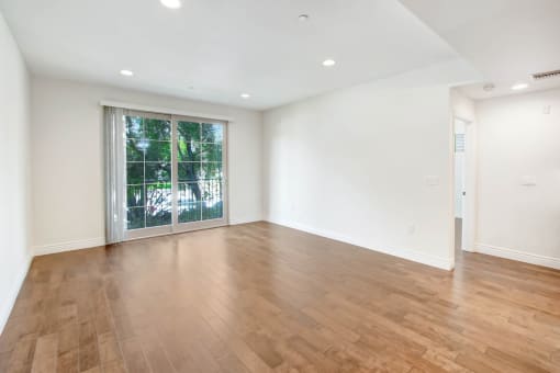an empty living room with a large window and wooden floors