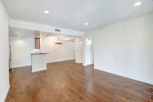 an empty living room with white walls and wood flooring