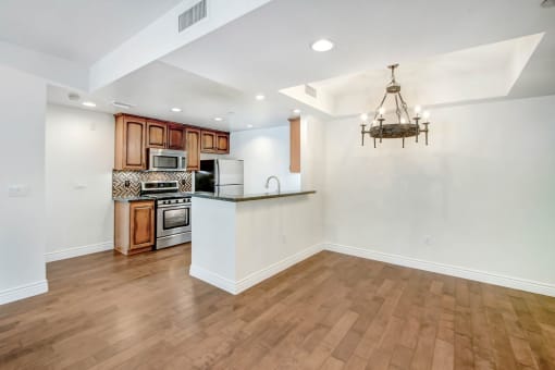 an empty living room with a kitchen and a chandelier