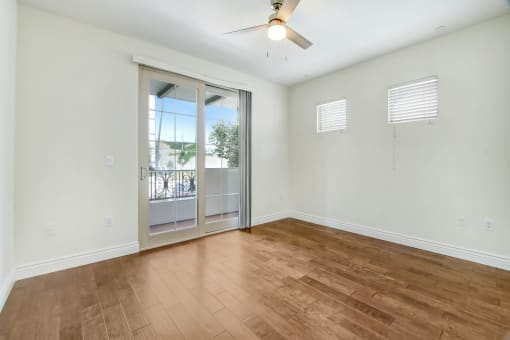 an empty living room with a sliding glass door to a balcony