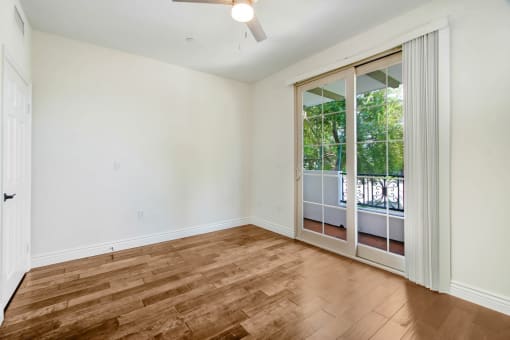 an empty living room with a sliding glass door to a balcony