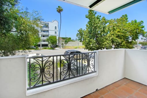 a balcony with a car parked on the street next to a wall and a railing