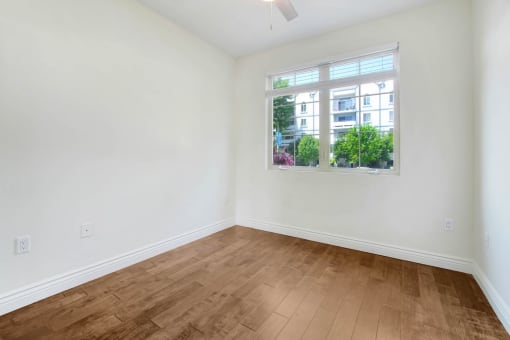 an empty living room with a window and wooden floors