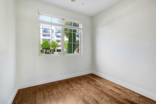 an empty room with a window and wooden floors