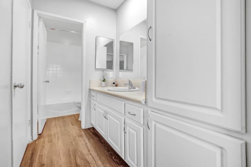 a bathroom with white cabinets and a sink and a mirror
