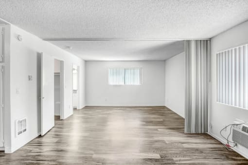 an empty living room with white walls and a wood floor