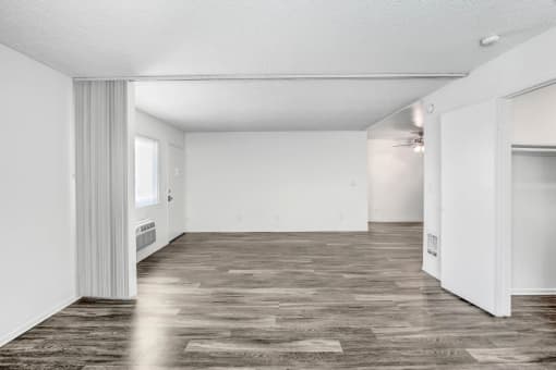 an empty living room with a wood floor and white walls