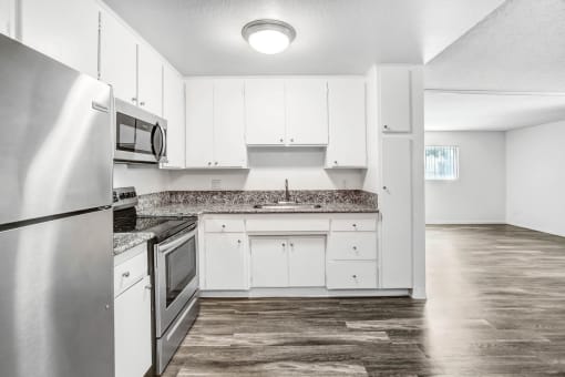 an empty kitchen with white cabinets and stainless steel appliances