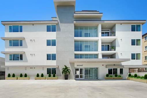 a large white apartment building with a large parking lot