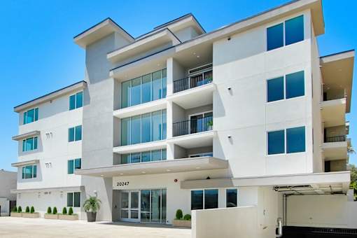 a large white apartment building with windows and a driveway