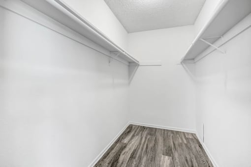 an empty room with white walls and wood flooring and a white closet