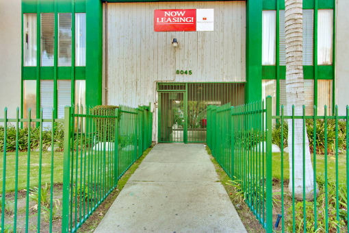 a green and white building with a sign that reads now leasing
