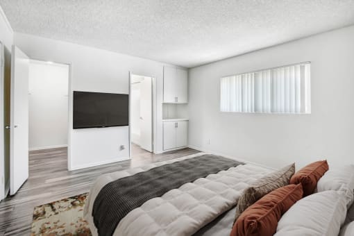 the master bedroom has a large bed and a tv on the wall