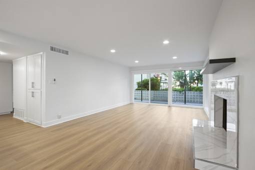 A spacious room with wooden floors and a fireplace.