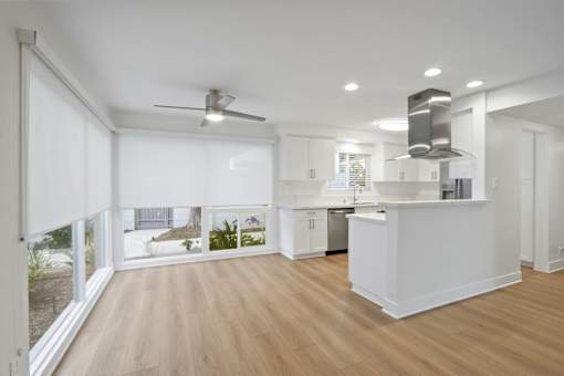 A modern kitchen with a large island and a ceiling fan.