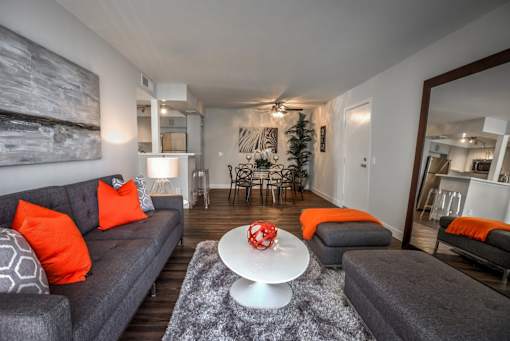 A living room with grey couches and orange pillows.