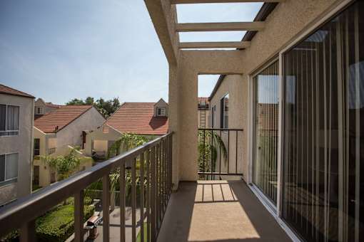 A balcony with a railing and a mat on the floor.