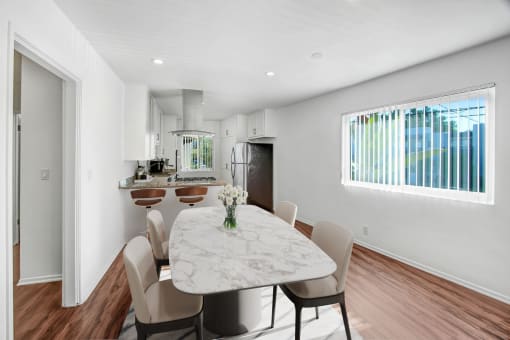 a dining area with a table and chairs and a kitchen in the background