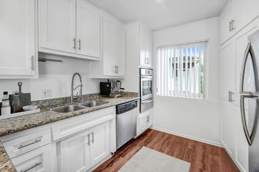 a kitchen with white cabinets and black counter tops and a window