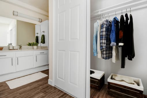 a bathroom with a white door and a closet with clothes hanging