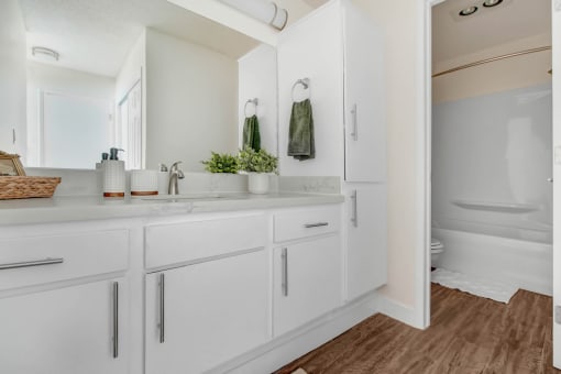 a white bathroom with a large mirror and white cabinets