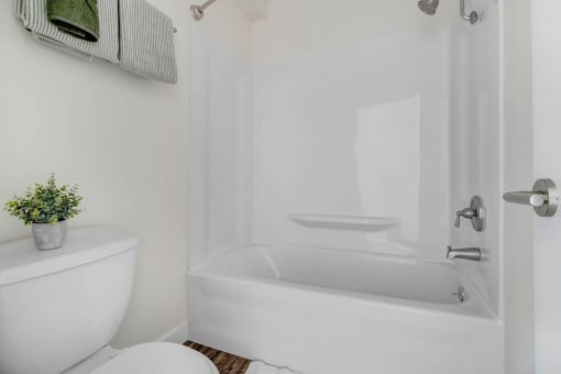 a white bathroom with a white toilet and a bath tub