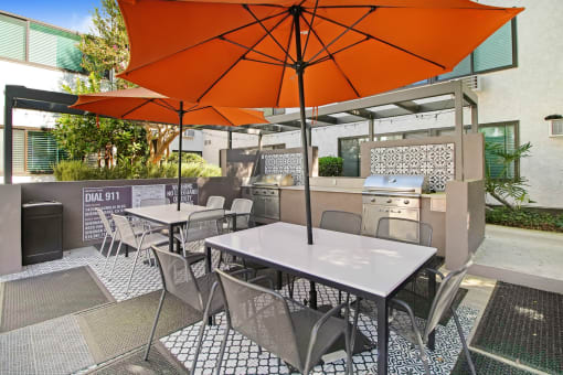a patio with tables and chairs and an orange umbrella