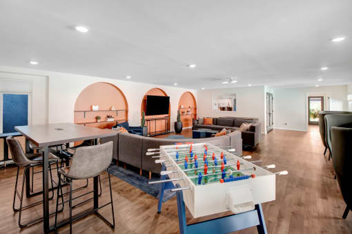 a living room with a table and chairs and a game table in the middle