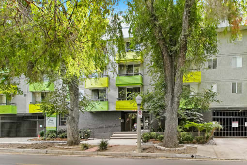 a building with green balconies and trees in front of it