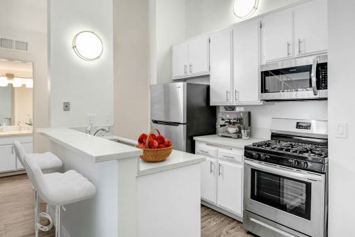 an apartment kitchen with stainless steel appliances and white cabinets
