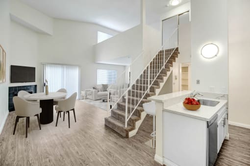 a living room and dining room with a staircase and a dining room table and chairs