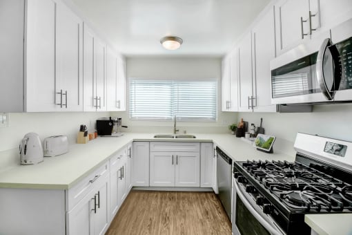 a kitchen with white cabinets and a stove and a microwave