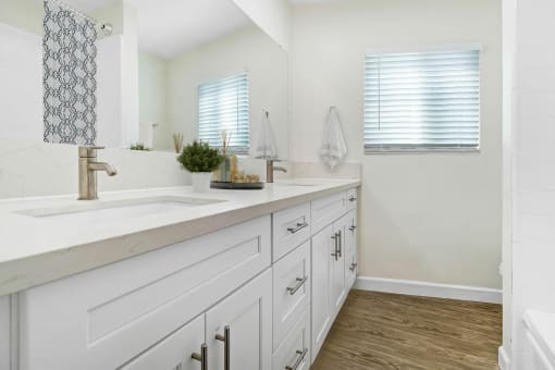 a bathroom with white cabinets and a sink and a mirror