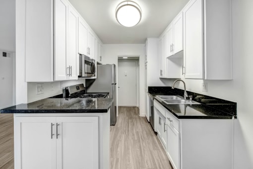 a white kitchen with white cabinets and black counter tops