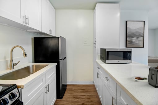 a kitchen with white cabinets and a sink and a refrigerator