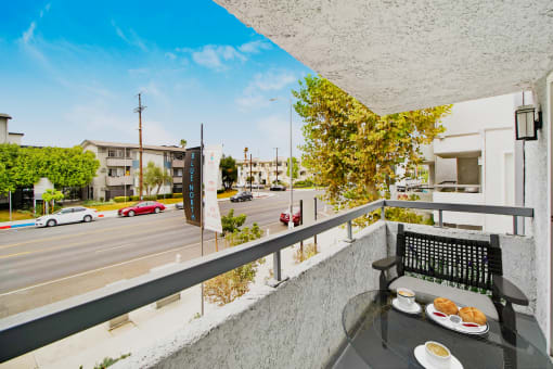 a balcony with a table with food on it and a street